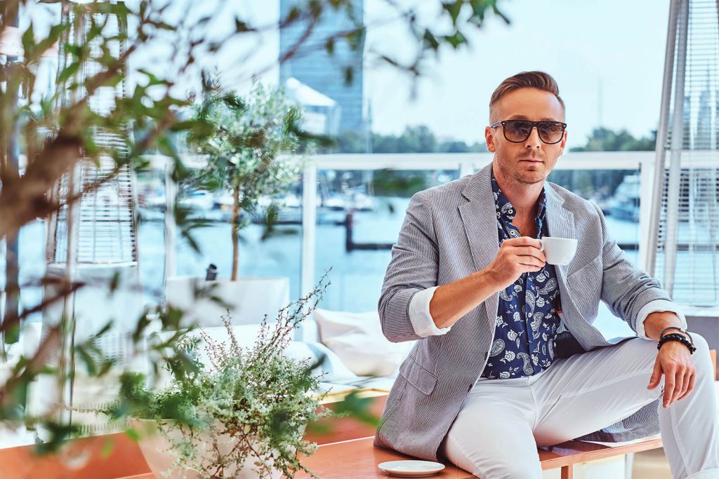 Successful man sips tea and relaxes by the waterside